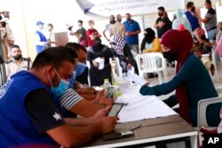 FILE - A vaccination campaign against the coronavirus is underway at a Tripoli shelter for migrants, organized jointly by the Libyan center for disease control and the International Organization for Migration. in Tripoli, Libya, Oct. 6, 2021.