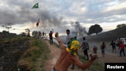 People hurl stones at the border between Santa Elena de Guairen, Venezuela, and Brazil in Pacaraima, Brazil, Feb. 23, 2019.