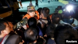 Para anggota keluarga penumpang kapal yang tenggelam mendorong polisi militer saat menuju Sungai Yangtze, provinsi Hubei, China (3/6). (Reuters/Kim Kyung-Hoon)
