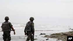 Navy officers walk along El Bosque beach, in Mexico's Tabasco state, Saturday, Sept. 10, 2011