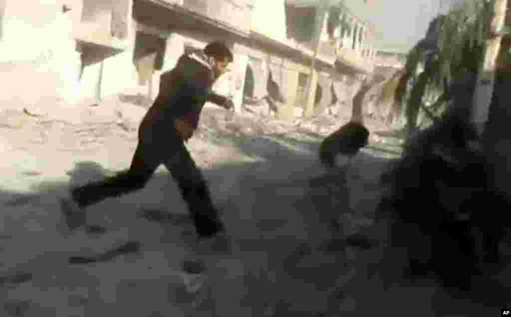 This image taken from video obtained from Shaam News Network shows men running during heavy bombing from military warplanes in Houla, Syria, November 6, 2012. 