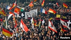 FILE - Supporters of anti-immigration movement Patriotic Europeans Against the Islamization of the West (PEGIDA) hold flags during demonstration in Dresden, Germany, Jan. 12, 2015.