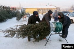People shop for a New Year's tree at a street market with the air temperature of about -28 degrees Celsius in Krasnoyarsk, Siberia, Dec. 27, 2018.