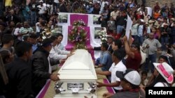 Friends and supporters gather next to the coffin of slain environmental rights activist Berta Caceres as they attend a Mass outside the Virgen de Lourdes church in the town of La Esperanza, outside Tegucigalpa, Honduras, March 5, 2016.