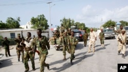 Somali soldiers patrol near the wreckage of a car bomb that was detonated at the main gate of the presidential palace in Mogadishu, July, 9, 2014. 