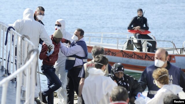 Migrantes son ayudados a desembarcar de un barco guardacostas italiano en el puerto de Palermo.
