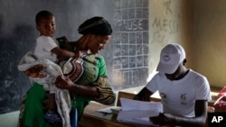 Une dame vote, son bébé sur le dos, au Burundi