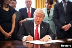 U.S. President Donald Trump signs an executive order cutting regulations, accompanied by small business leaders at the Oval Office of the White House in Washington, Jan. 30, 2017.