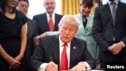 U.S. President Donald Trump signs an executive order cutting regulations, accompanied by small business leaders at the Oval Office of the White House in Washington, Jan. 30, 2017. 