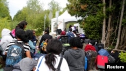 Barisan para pencari suaka yang mengaku dari Haiti menunggu untuk masuk ke Kanada dari Roxham Road di Champlain, New York, 7 Agustus 2017.