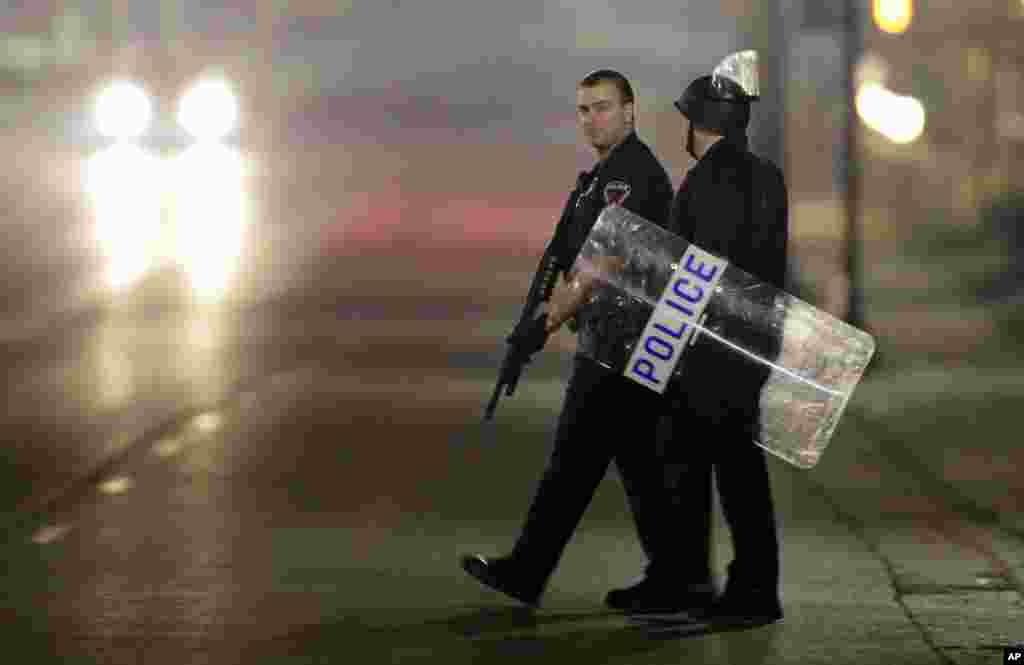 Police canvass the area as they investigate the scene where two police officers were shot outside the Ferguson Police Department.