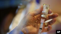 FILE - In this Dec. 29, 2020, file photo, Pat Moore, with the Chester County, Pa., Health Department, fills a syringe with Moderna COVID-19 vaccine before administering it to emergency medical workers and health care personnel at the Chester County Govern