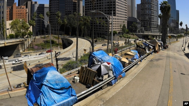 FILE - This May 21, 2020, file photo shows a homeless encampment on Beaudry Avenue as traffic moves along Interstate 110 in downtown Los Angeles. Over three days and nights this week, census takers are going to shelters, soup kitchens, mobile food van sto