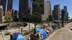 FILE - This May 21, 2020, file photo shows a homeless encampment on Beaudry Avenue as traffic moves along Interstate 110 in downtown Los Angeles. Over three days and nights this week, census takers are going to shelters, soup kitchens, mobile food van sto