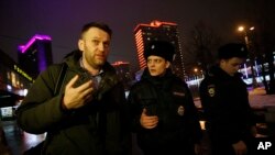 Russian opposition activist Alexei Navalny, left, is briefly detained by police officers after defying his house arrest to speak on Radio Ekho Moskvy in Moscow, Jan. 14, 2015.
