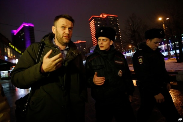 FILE - Russian opposition activist Alexei Navalny, left, is briefly detained by police after defying his house arrest to speak on Radio Ekho Moskvy in Moscow, Jan. 14, 2015.