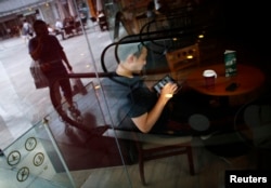 FILE - A man surfs the Internet on his tablet device at a coffee shop in downtown Shanghai, Sept. 25, 2013. The U.S. embassy in Beijing is taking a break from publicly engaging Chinese people through social media.