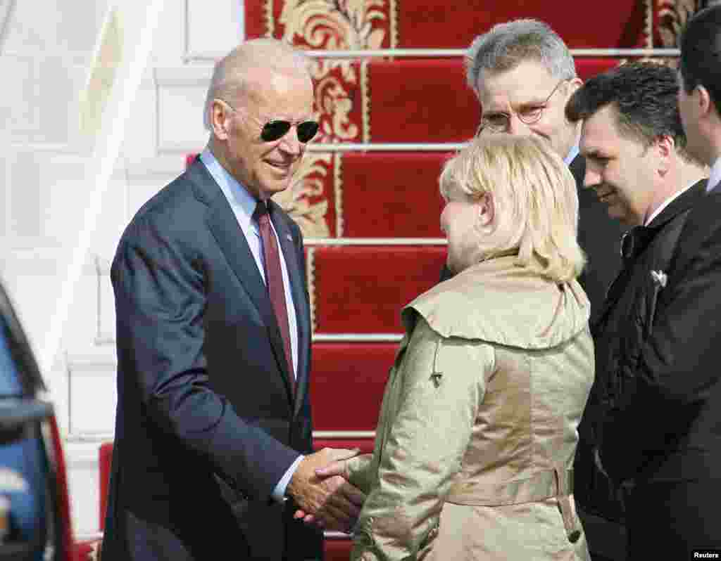 Wakil Presiden AS Joe Biden (kiri) berjabat tangan dengan para pejabat Ukraina dan AS saat tiba di bandar udara internasional Boryspil di luar kota Kyiv, Ukraina (21/4). (Reuters/Valntyn Ogirenko)