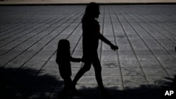 Una mujer y una niña caminan durante una marcha contra el tráfico humano y la esclativud en Ciudad de México el 14 de octubre de 2017.