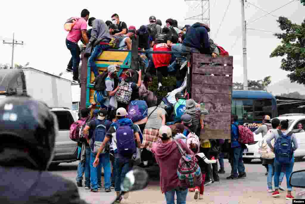 Hondurans climb onto the back of a vehicle for a ride in a new caravan of migrants set to head to the United States, in Cofradia, Honduras.