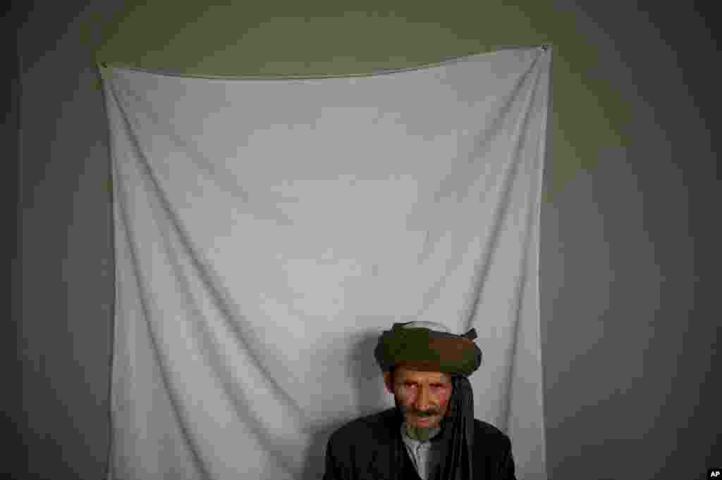 A man waits to have his picture taken for his registration card on the last day of voter registration for the upcoming presidential elections outside a school in Kabul, April 1, 2014. 