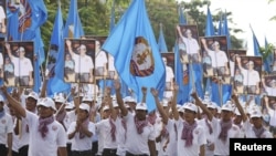 Supporters of the ruling Cambodian Peoples Party (CPP) march with party flags, posters