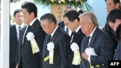 Le Secrétaire général de l'ONU, Antonio Guterres, à droite, et le Premier ministre japonais, Shinzo Abe (à gauche), assistent à une cérémonie commémorant le 73e anniversaire du bombardement atomique de Nagasaki, au parc commémoratif de la paix à Nagasaki, au Japon, le 9 août 2018.