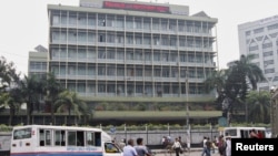 FILE - Commuters pass by the front of the Bangladesh central bank building in Dhaka.