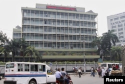 FILE - Commuters pass by the front of the Bangladesh central bank building in Dhaka.