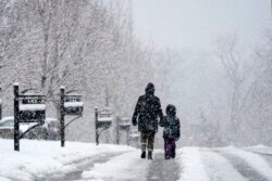 Orang-orang berjalan-jalan saat salju turun Minggu, 16 Januari 2022, di Nolensville, Tennessee (AP Photo/Mark Humphrey)