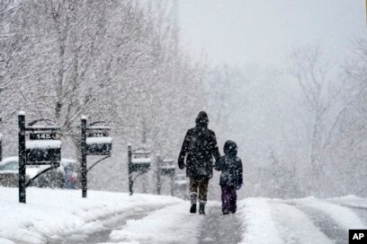 Orang-orang berjalan-jalan saat salju turun Minggu, 16 Januari 2022, di Nolensville, Tennessee (AP Photo/Mark Humphrey)