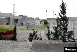 FILE - A Hezbollah flag flutters in a government-controlled area, as seen from the rebel-controlled area of Karm al-Tarab frontline, near Aleppo international airport April 22, 2015.