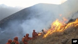 In this Sunday, Dec. 5, 2010 photo, paramilitary firemen fight a grassland fire near Zilong village in Daofu county, in southwest China's Sichuan Province. At least 22 people have died after the grassland fire they were fighting in southwestern China turn