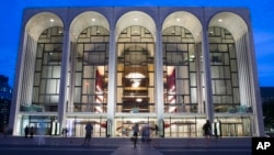 FILE - Pedestrians walk in front of the Metropolitan Opera house at New York's Lincoln Center, Aug. 1, 2014. New York's Metropolitan Opera stopped a performance Saturday after someone sprinkled an unknown powder into the orchestra pit. 