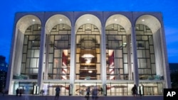 FILE - Pedestrians walk in front of the Metropolitan Opera House at New York's Lincoln Center, Aug. 1, 2014. 