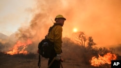 Seorang petugas pemadam kebakaran di menyaksikan api dekat Jalan Placenta Caynon Road di Santa Clarita, California (24/7). (AP/Ringo H.W. Chiu)