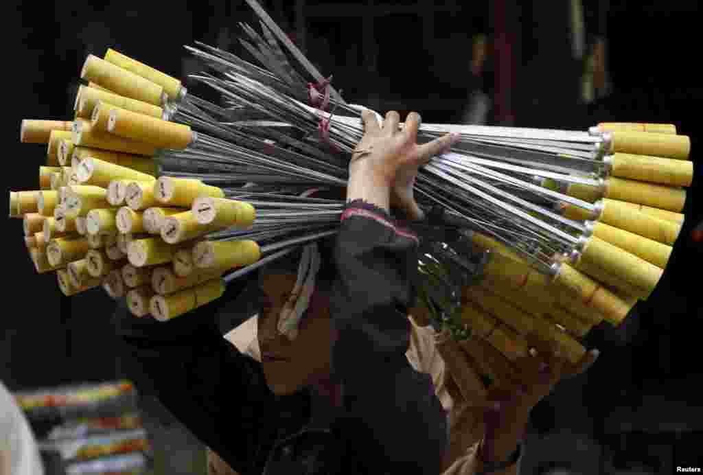 A boy carries skewers to be sold as the Eid holiday begins in Peshawar, Pakistan.