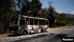 Men walk past a bus that was torched during protests in the town of Sebeta, Oromia region, Ethiopia, Oct. 8, 2016.