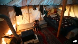 Syrian refugee children sit inside their tent at a small refugee camp, in Ketermaya village southeast of Beirut, Lebanon, March 14, 2013.