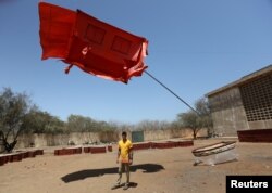 Marcos Lora Read poses for a photo with his artwork "La Casa Roja" during the 13th edition of the Dakar Biennale of African Contemporary Art, Dak'art in Dakar, Senegal, May 4, 2018.