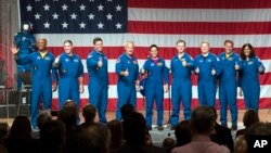 Astronauts, from left, Victor Glover, Michael Hopkins, Robert Behnken, Douglas Hurley, Nicole Mann, Christopher Ferguson, Eric Boe, Josh Cassada and Sunita Williams give a thumbs up to the crowd after NASA announced them as astronauts assigned to crew the first flight tests and missions of the Boeing CST-100 Starliner and SpaceX Crew Dragon, Aug. 3, 2018, in Houston.