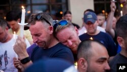 Paul Cox, right, leans on the shoulder of Brian Sullivan, as they observe a moment of silence during a vigil for a fatal shooting at an Orlando nightclub, June 12, 2016, in Atlanta, Georgia.