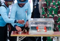 Personel TNI AL memegang kotak berisi perekam data penerbangan yang ditemukan dari lokasi jatuhnya penerbangan Sriwijaya Air SJ-182 di Laut Jawa di Pelabuhan Tanjung Priok. (Foto: AP)