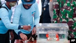 Personel TNI AL memegang kotak berisi perekam data penerbangan yang ditemukan dari lokasi jatuhnya penerbangan Sriwijaya Air SJ-182 di Laut Jawa di Pelabuhan Tanjung Priok. (Foto: AP)