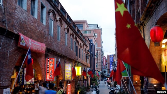 台湾金门一条街道商店旁插有中国和台湾的旗帜。(2018年8月19日)
