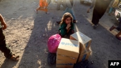 A displaced Syrian child who fled from Raqa, sits behind humanitarian aid boxes delivered by UNICEF at a temporary camp in the town of Tabqa, about 55 kilometres (35 miles) west of Raqa.