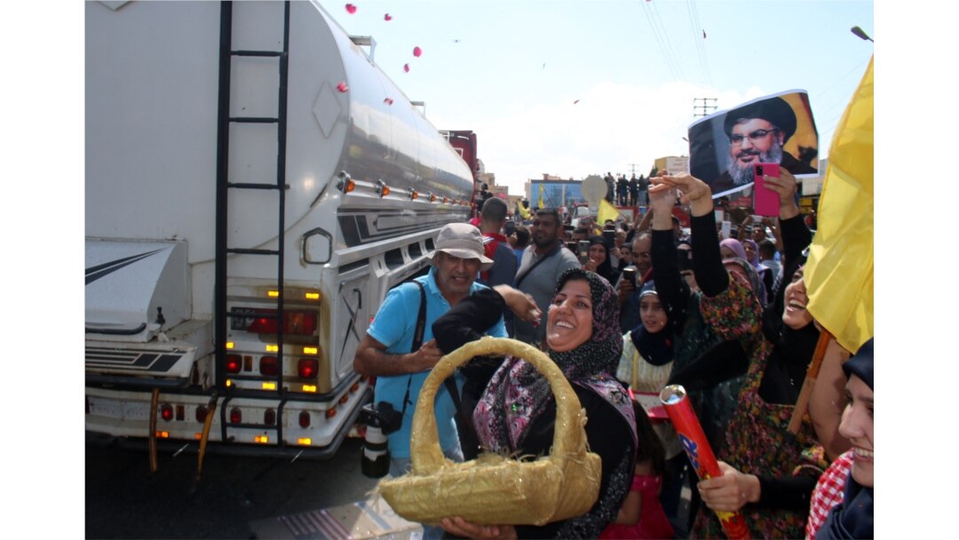 Seorang perempuan menaburkan mawar saat orang-orang berkumpul untuk menyambut kapal tanker yang membawa bahan bakar dari Suriah tiba di kota Baalbeck, di lembah Bekaa, Lebanon, 16 September 2021.