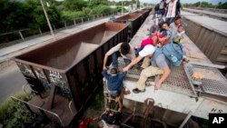 FILE - A young boy is is helped down from the top of a freight car, as Central Americans board a northbound freight train in Ixtepec, Mexico.