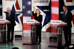 Hillary Clinton waves as Bernie Sanders, left, and Martin O'Malley prepare before a Democratic presidential primary debate, Nov. 14, 2015, in Des Moines, Iowa.