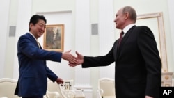 Russian President Vladimir Putin, right, greets Japanese Prime Minister Shinzo Abe prior their talks in the Kremlin in Moscow, Russia, Tuesday, Jan. 22, 2019. 